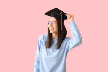 Wall Mural - Young female graduate on pink background