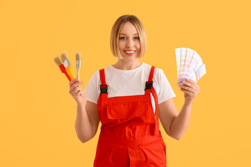 Wall Mural - Female decorator with color samples and brushes on yellow background