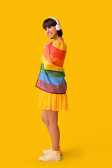 Poster - Beautiful young woman in headphones with LGBT flag on yellow background