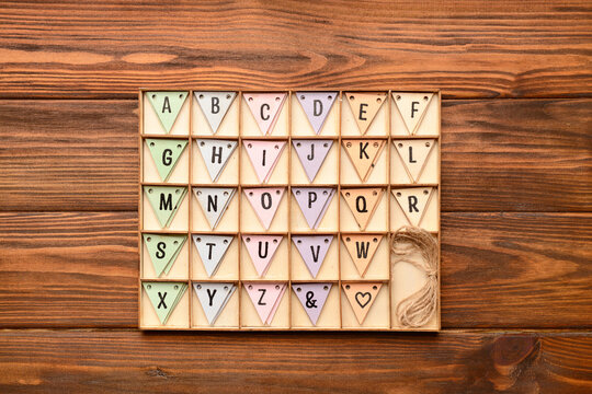 Alphabet in wooden box on wooden background. Top view
