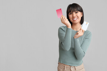 Poster - Beautiful young woman with credit cards on grey background