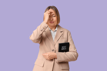 Wall Mural - Adult woman with Holy Bible cross oneself on lilac background