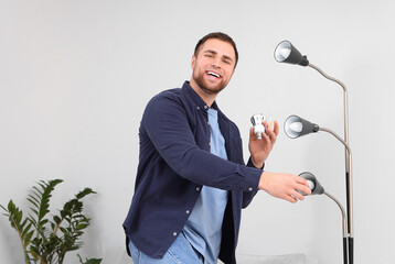 Wall Mural - Young man changing light bulbs in standard lamp at home