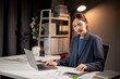 © Wasana - A woman is sitting at a desk with a laptop open in front of her
