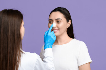 Sticker - Plastic surgeon and young woman with bandaged nose on lilac background