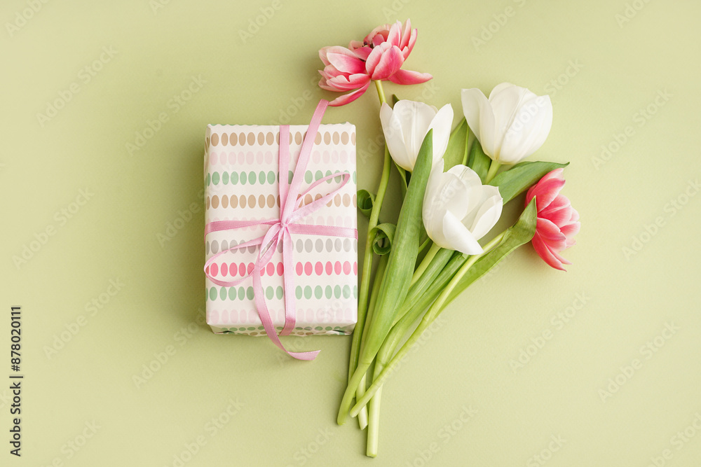 Gift box and beautiful tulips on green background