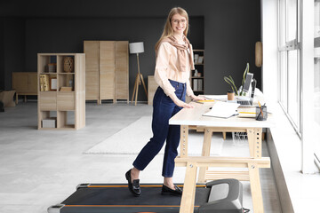 Sticker - Young businesswoman training on treadmill at table in office