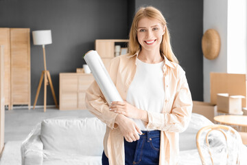 Wall Mural - Young woman with stretch wrap in room on moving day