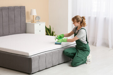 Canvas Print - Female janitor cleaning mattress with brush and detergent in bedroom