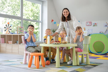 Canvas Print - Little children with nursery teacher having lunch in kindergarten