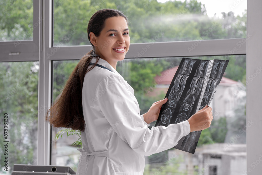 Female doctor studying x-ray image near window in clinic