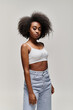 © LIGHTFIELD STUDIOS - A stylish African American woman with curly hair wearing a crop top and jeans.