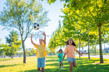 Kids Playing Soccer in the Park on a Sunny Day. Three children playing soccer in a sunny park, enjoying a fun outdoor activity.