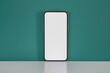 © photology1971 - Smartphone with a blank screen placed on a white desk against a green wall