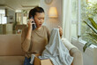 © DragonImages - Upset customer making phone call about her defective order while sitting on sofa in the living room
