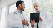 © peopleimages.com - Healthcare, doctors and discussion with tablet in hospital for medical research, cardiology and advice. Low angle, man and mentor with tech for diagnosis, solution and good review of patient surgery