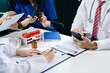 © Nuttapong punna - Medical team having a meeting with doctors in white lab coats and surgical scrubs seated