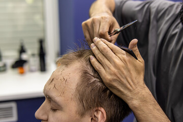 Professional male hairdresser at work. Barbershop. Young man gets haircut at barbershop. Cutting hair with scissors closeup