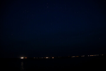 Wall Mural - Starry sky and burning lights on the horizon