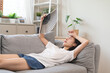 © Pormezz - Suffering summer heat wave stroke, hot weather, tired asian young woman feeling discomfort sweaty, sitting on couch in living room, hand fan in blowing, wave fan to ventilation when high temperature.
