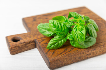 Green basil leaves on a textured wooden background. Kitchen herbs, spices. Fresh green organic basil. Vegan. Greens for salad. Place for text. Copy space.