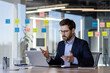 © Liubomir - Professional businessman in a modern office having a video call while discussing a project. He is surrounded by colorful sticky notes on a glass wall, demonstrating a collaborative and organized