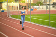 © yavdat - woman, dressed in blue athletic gear, jogs on a track, showcasing her dedication to a regular fitness routine. This photo emphasizes the benefits of running for building stamina and cardiovascular