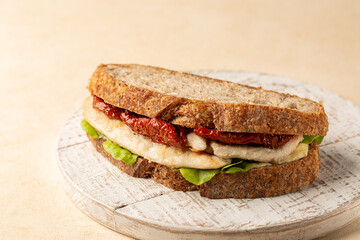 Poster - Healthy Chicken breast sandwich with whole wheat bread, ricotta cheese, lettuce, and sun dried tomatoes on a white board.