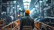 © M - Industry worker from behind with safety jacket and helmet at industrial plant looking at the factory, Heavy industrial concept, Back view of worker with yellow safety helmet in factory, AI generated