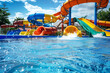 © Jana - Water park with colorful slides and splashes in the pool, summer vacation activity for family or friends on holiday at outdoor waterpark or aquapark .