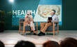© peopleimages.com - Speaker, health seminar and speech of woman on stage with host on mic and tablet at event. Workshop, talk and conference presentation on wellness, medicine or medical innovation of drugs with guest