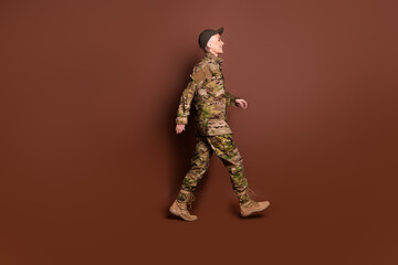 Sticker - Full size photo of pretty senior female brave servicewoman walk profile wear camouflage military uniform isolated on brown color background