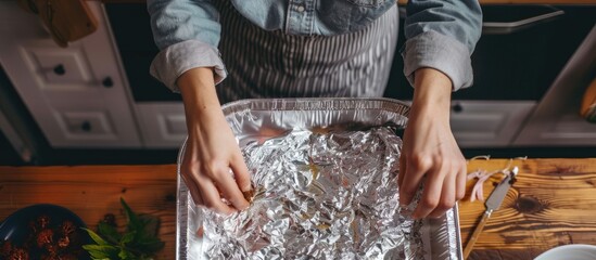 Aufkleber - Close-up image of a baking pan with aluminum foil on a kitchen table. Detailed steps of baking process; a woman's hands preparing a cake, top-down view, with copy space image.