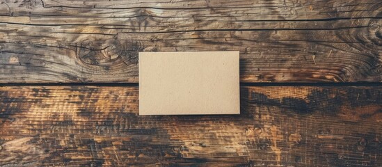 Mock-up of a business card on a wooden background with copy space image. Corporate branding stationery for a creative designer's desk in a flat lay layout.