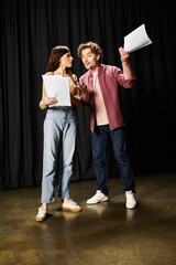 Wall Mural - A stylish man and woman pose in front of a mysterious black curtain during theater rehearsals.