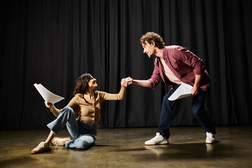 Wall Mural - A handsome man kneels beside a woman on the floor in a theatrical setting.