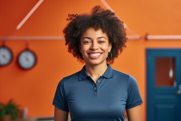 Wall Mural - Portrait of a grinning afro-american woman in her 30s wearing a sporty polo shirt in front of vibrant yoga studio background