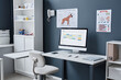© Seventyfour - Background image of modern veterinarian workplace with dog breeds posters on blue wall, medical supplies and desktop computer displaying calendar page with week appointments