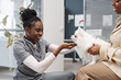 © Seventyfour - Happy female African American vet expert with stethoscope meeting adorable pomeranian dog on owners hands right before physical examination in vet clinic waiting room, copy space