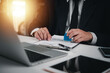 © khunkornStudio - Businessman in suit stamping a document, approving contract. Professional corporate setup for legal agreements, official paperwork. Signature, authority process.