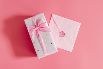 Wall Mural - One gift box with an envelope on a pink background.