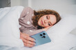 © deagreez - Photo of pretty young girl lay bed use phone wear pajama bright interior bedroom apartment indoors