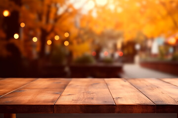 Wall Mural - Empty wooden table in front autumn leaves trees in park blurred background banner for product display in a coffee shop, local market or bar	