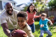 © MarGa - A diverse family playing football in the backyard, smiling and having fun. Concept for family bonding and outdoor activities