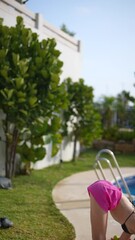 Wall Mural - A woman enjoying summertime by stretching near the pool, surrounded by nature and sunshine