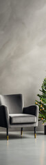 A minimalist grey armchair and a Christmas tree with gold ornaments in a modern interior with grey walls and a grey floor. 
