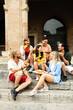 © Xavier Lorenzo - Vertical shot of diverse group of happy friends eating pizza sitting together at city street while enjoying summer vacation in Italy.
