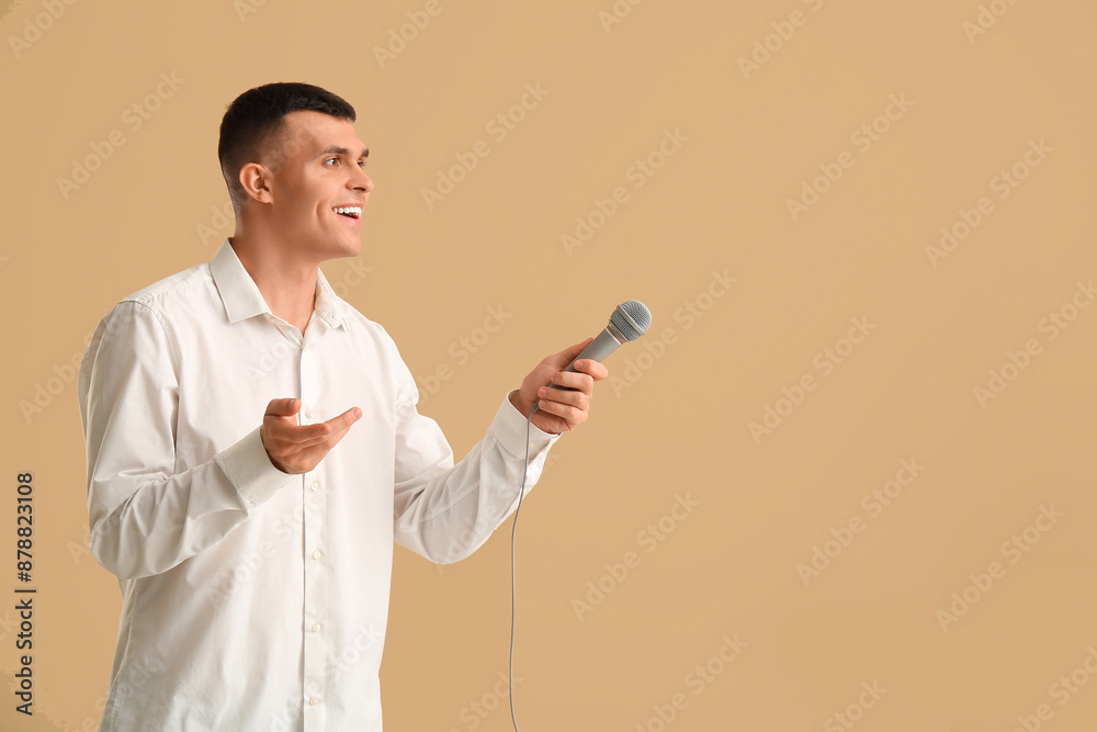 Young man with microphone on brown background