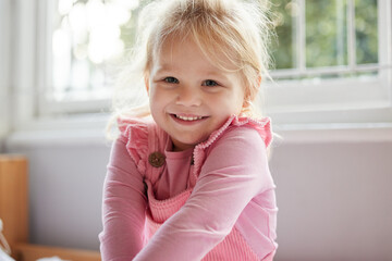 Canvas Print - Happy girl, portrait and relax with toddler by window for childhood development at home. Young child, kid or blonde female person with adorable, cute or innocent smile in joy for youth at house