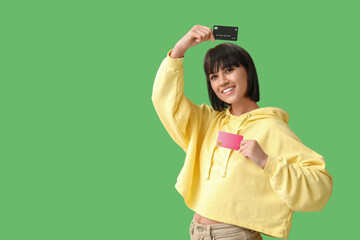 Poster - Beautiful young woman with credit cards on green background